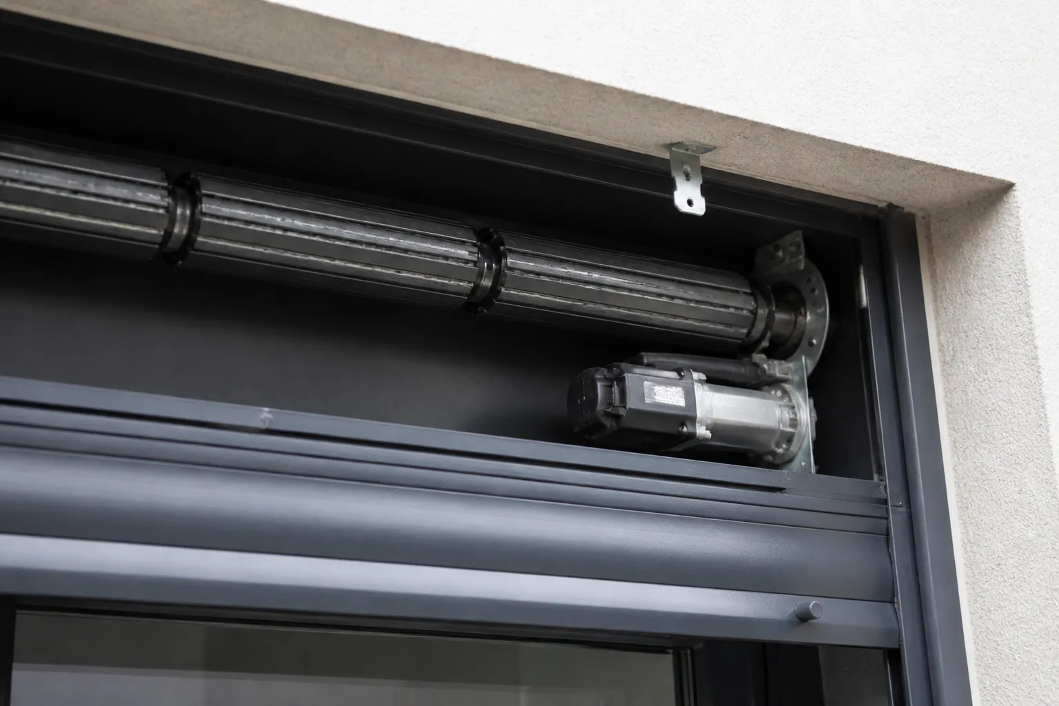 Coffre de volet roulant ouvert, axe d’enroulement et moteur électrique visibles