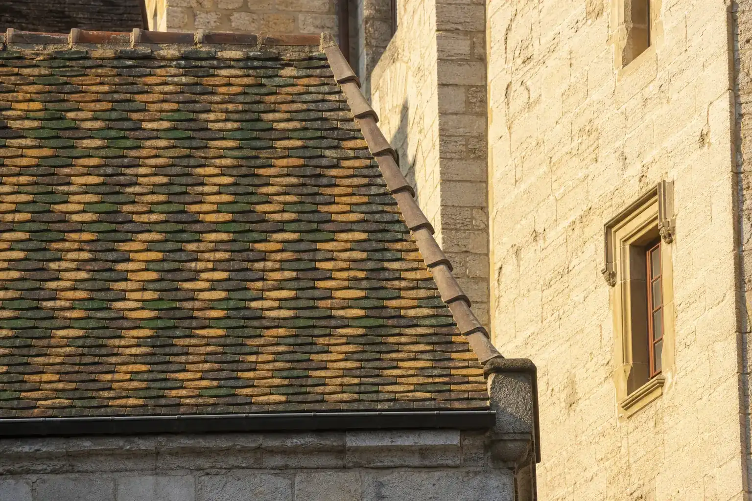 Toit de tuiles vernissées polychromes bourguignonnes juxtaposé à une façade en pierre de Bourgogne
